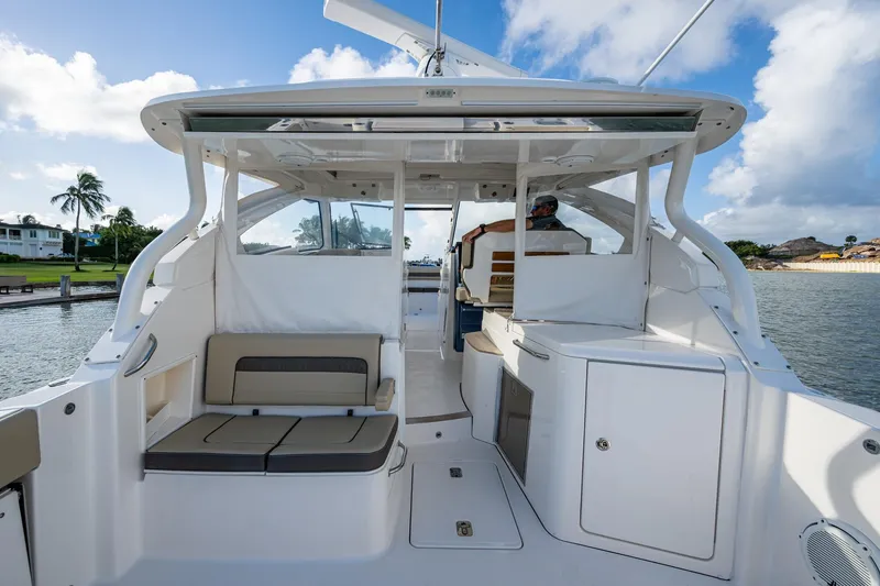 Slide: The Image of 2019 Pursuit DC 365 Dual Console boat interior with seating and helm, docked by water. - 18