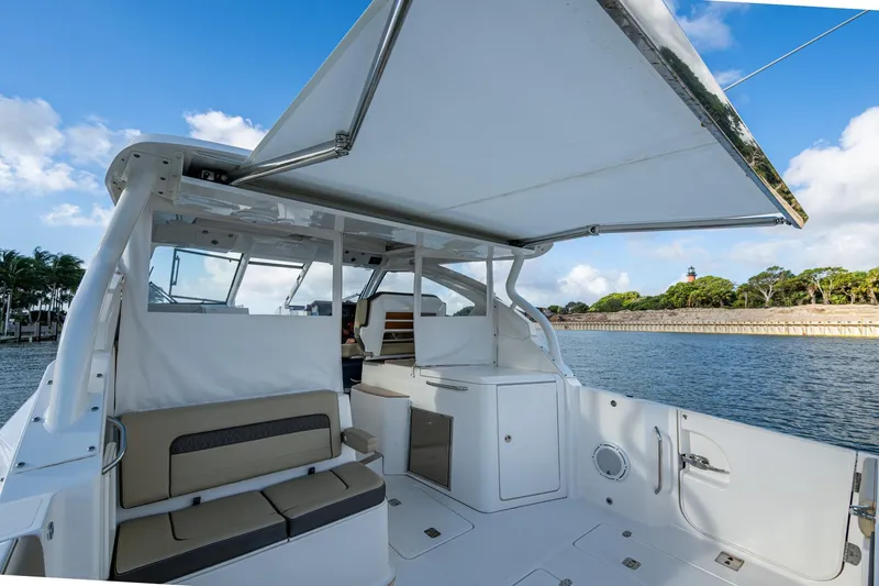 Slide: The Image of 2019 Pursuit DC 365 Dual Console boat interior with seating and canopy, near waterfront. - 20