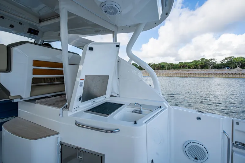 Slide: The Image of 2019 Pursuit DC 365 Dual Console boat interior with sink and seating, near water. - 21