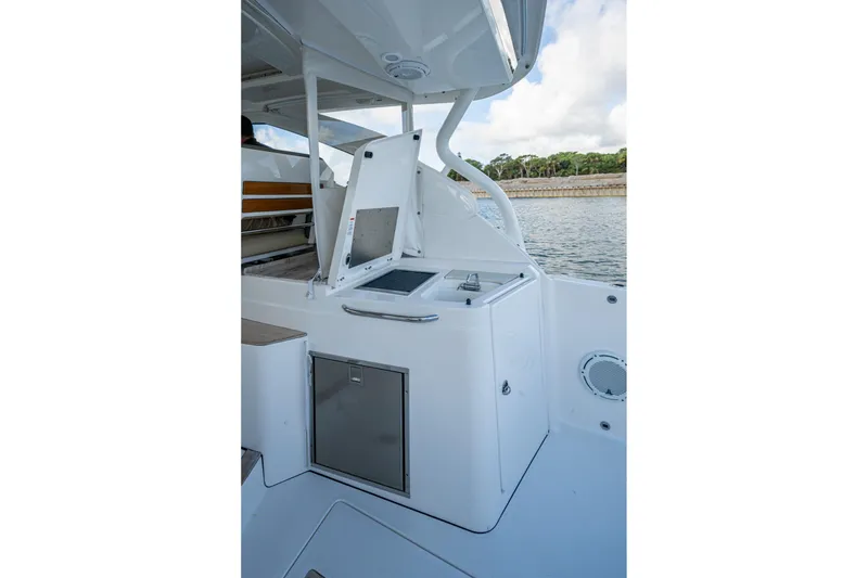 Slide: The Image of 2019 Pursuit DC 365 Dual Console boat interior with open storage compartment by the water. - 22