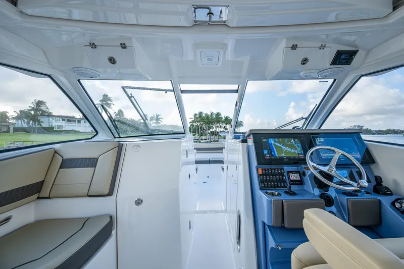 Slide: The Image of 2019 Pursuit DC 365 Dual Console interior with modern helm and seating, overlooking scenic waterfront. - 37