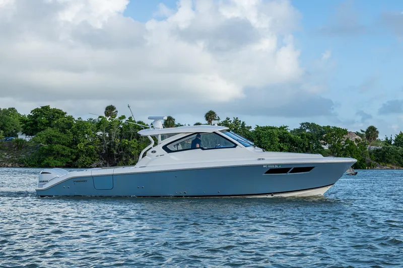 Slide: The Image of 2019 Pursuit DC 365 Dual Console boat cruising on a scenic waterway. - 40