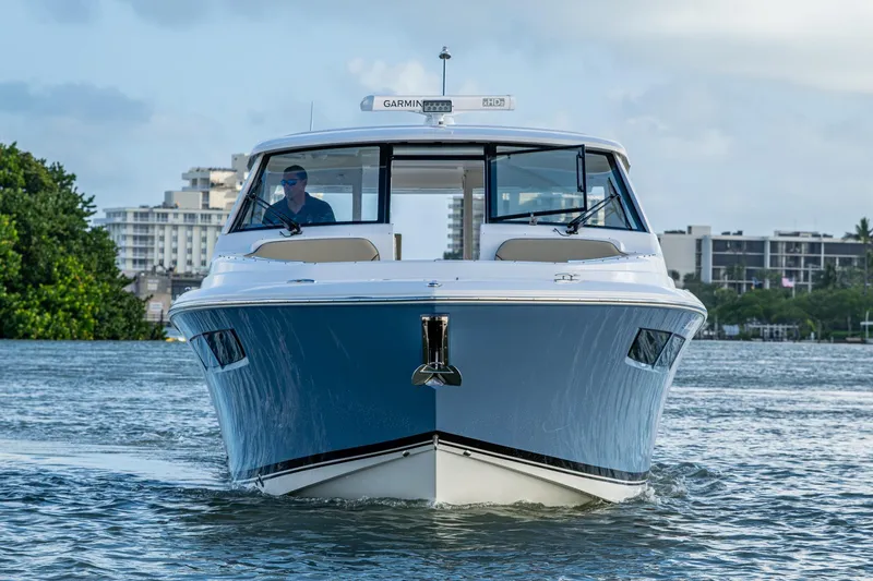 Slide: The Image of 2019 Pursuit DC 365 Dual Console boat cruising on water, cityscape background. - 43