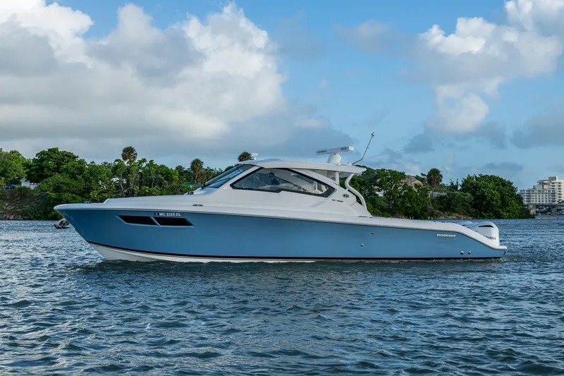 Slide: The Image of 2019 Pursuit DC 365 Dual Console boat on calm water, blue sky background. - 45