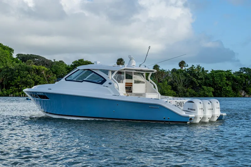 Slide: The Image of 2019 Pursuit DC 365 Dual Console boat on water, surrounded by lush greenery. - 47