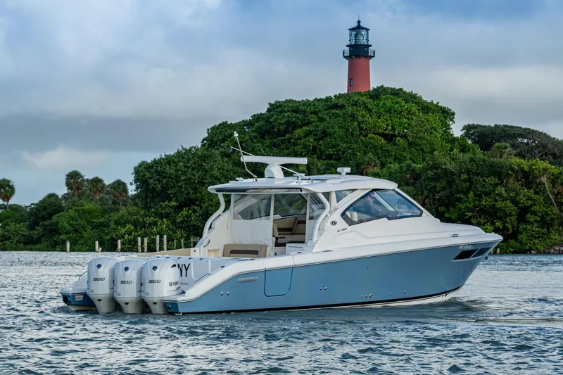 Slide: The Image of 2019 Pursuit DC 365 Dual Console boat cruising near a lighthouse and lush greenery. - 49