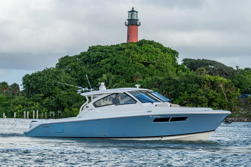 Slide: The Image of 2019 Pursuit DC 365 Dual Console boat cruising near lush greenery and lighthouse. - 50