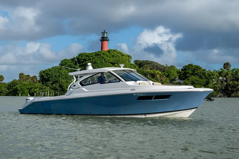 Slide: The Image of 2019 Pursuit DC 365 Dual Console boat cruising near a lighthouse and lush greenery. - 51