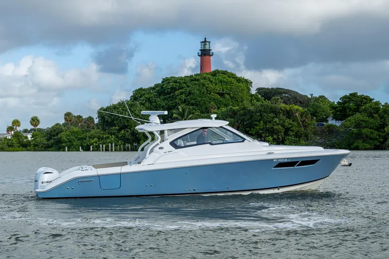 Slide: The Image of 2019 Pursuit DC 365 Dual Console boat cruising near lush greenery and lighthouse. - 54
