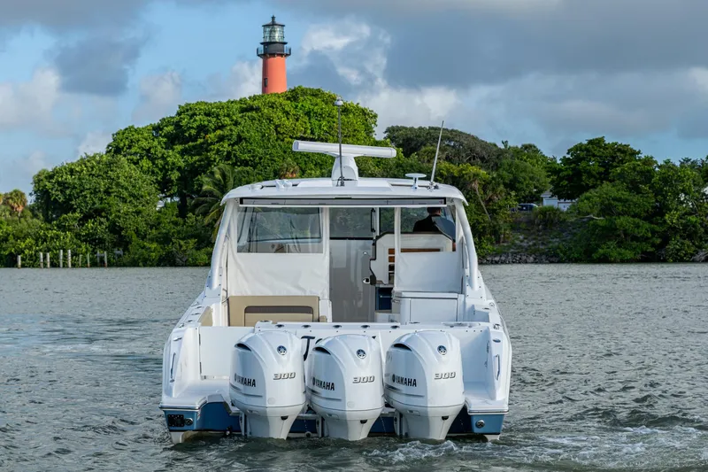 Slide: The Image of 2019 Pursuit DC 365 Dual Console boat with triple Yamaha engines near a lighthouse. - 55