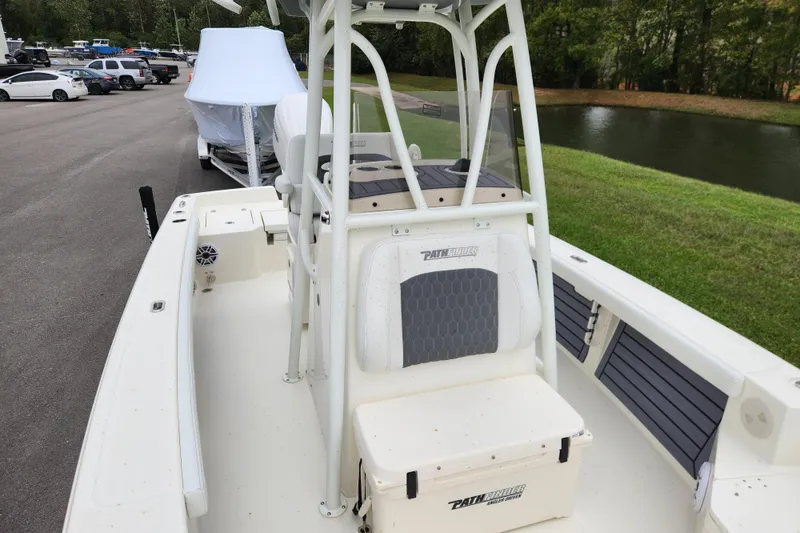 Slide: The Image of 2026 Pathfinder 2400 TRS boat, white interior, parked near a pond and vehicles. - 8