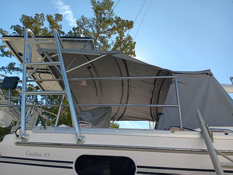 Slide: The Image of 2020 Catalina 315 sailboat with canopy and ladder, docked under clear sky. - 5