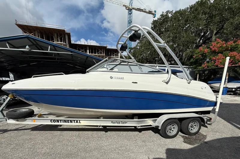 Slide: The Image of 2009 Yamaha AR230 HO boat on trailer, parked outdoors with construction in background. - 6