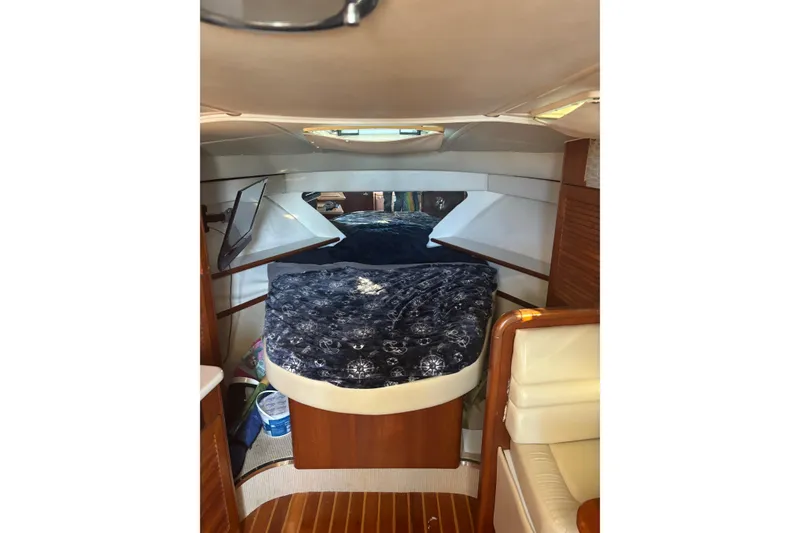 Slide: The Image of 2000 Pursuit 3400 Express boat interior with seating and ladder, docked near palm trees. - 26