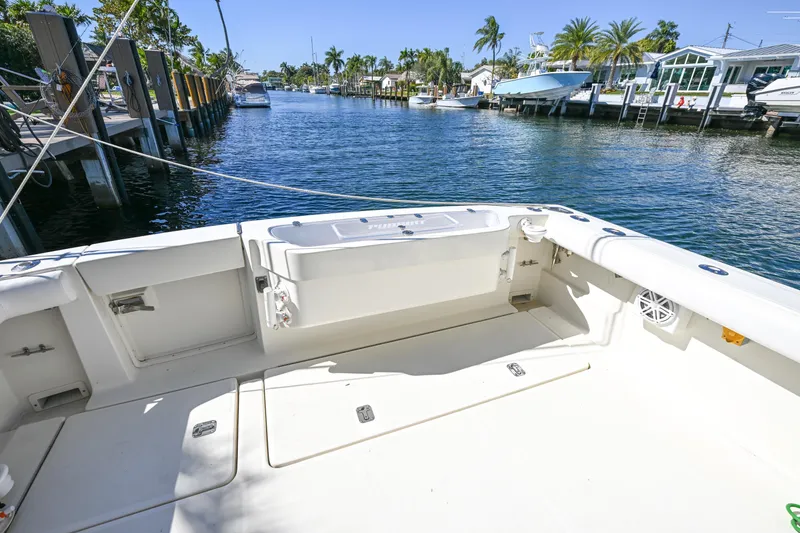 Slide: The Image of 2000 Pursuit 3400 Express boat docked by a scenic waterfront with palm trees. - 28
