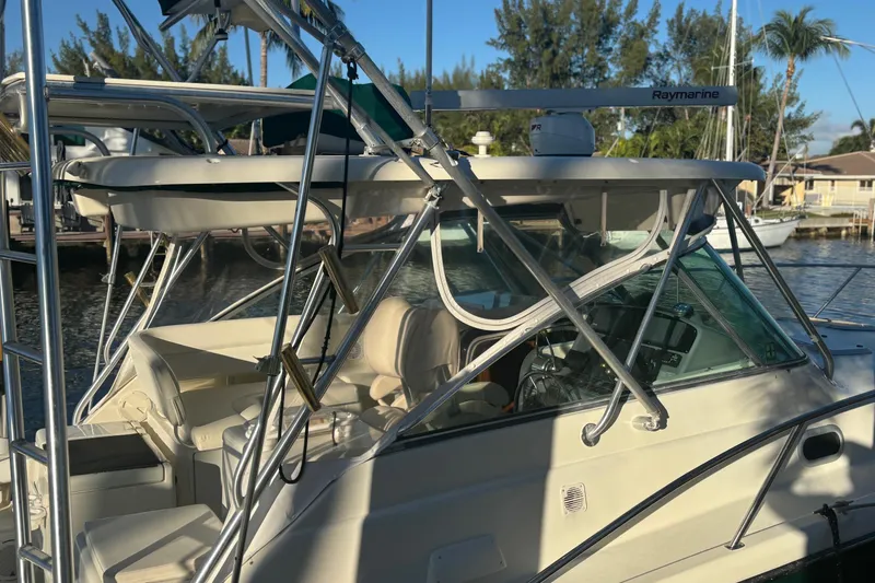 Slide: The Image of 2000 Pursuit 3400 Express boat docked by palm trees and waterfront property. - 3