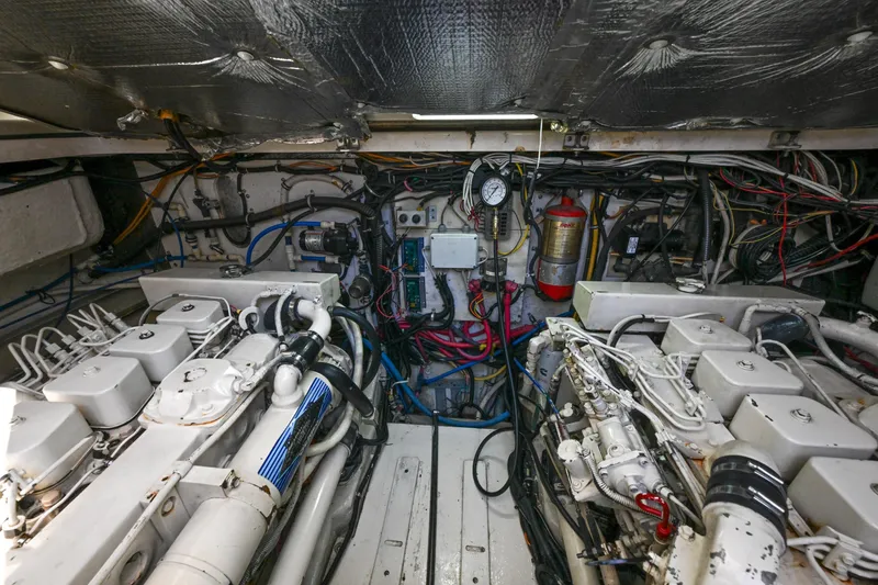 Slide: The Image of Engine room of a 2000 Pursuit 3400 Express boat, showcasing complex machinery and wiring. - 52