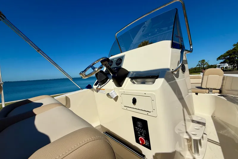Slide: The Image of 2026 Scout 195 Sportfish boat interior with steering console, beige seating, and ocean view. - 18