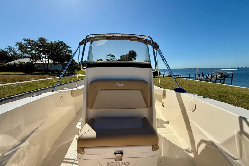 Slide: The Image of 2026 Scout 195 Sportfish boat interior with seating, dockside view, and clear blue sky. - 23