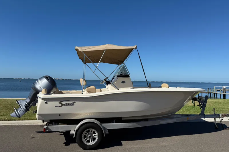 Slide: The Image of 2026 Scout 195 Sportfish boat on trailer by waterfront, clear blue sky. - 5