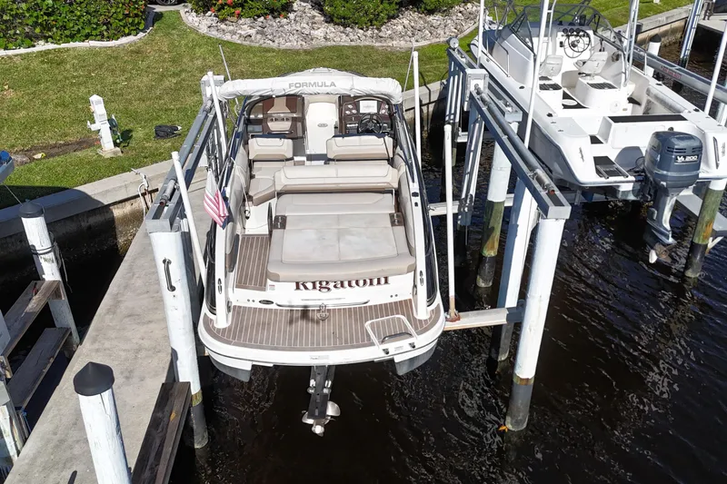 Slide: The Image of 2014 Formula 240 Bowrider boat docked on lift, rear view, sunny day. - 14