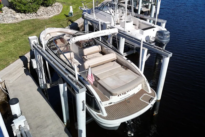 Slide: The Image of 2014 Formula 240 Bowrider boat docked on a lift by the water. - 21