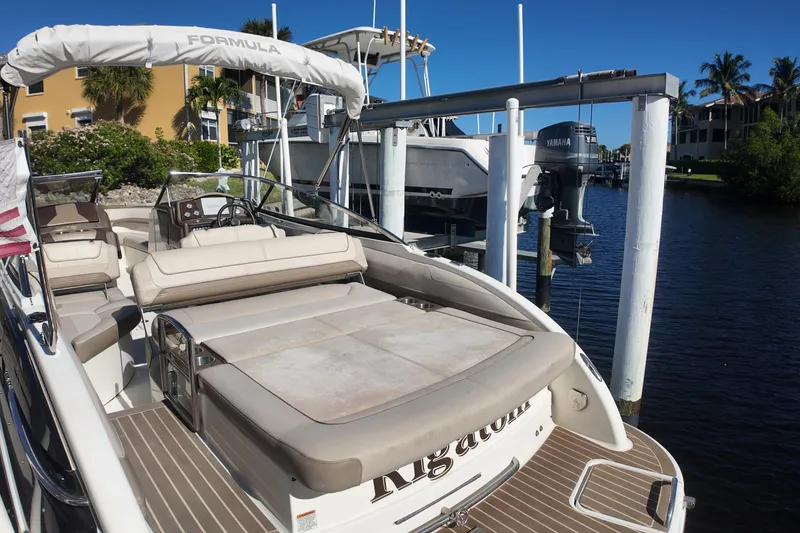 Slide: The Image of 2014 Formula 240 Bowrider boat docked by the water, featuring spacious seating and sleek design. - 22