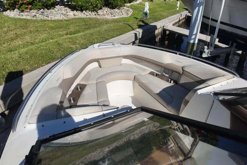 Slide: The Image of 2014 Formula 240 Bowrider boat with spacious seating and cup holders, docked near lush greenery. - 38