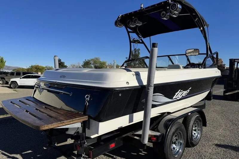 Slide: The Image of 1999 Tigé 2100V Limited boat on trailer, black and white design, outdoor setting. - 12