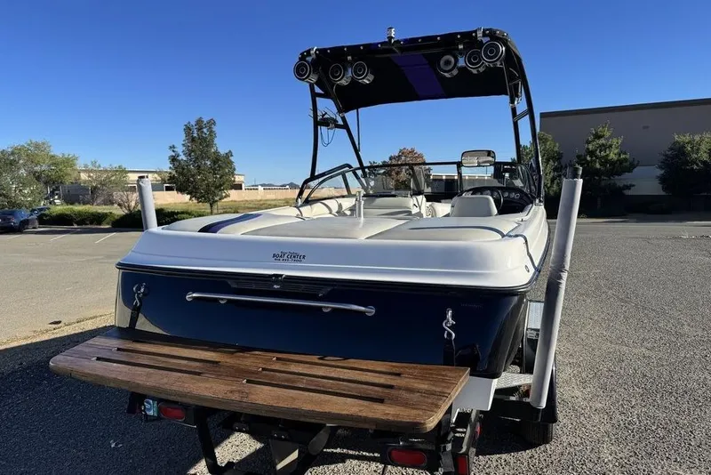 Slide: The Image of 1999 Tigé 2100V Limited boat on trailer, parked outdoors under clear blue sky. - 13