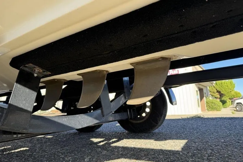 Slide: The Image of 1999 Tigé 2100V Limited boat trailer with visible fins and wheel on pavement. - 18