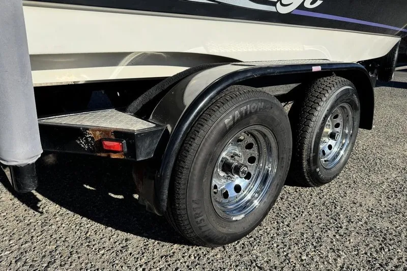 Slide: The Image of 1999 Tigé 2100V Limited boat trailer with dual wheels on asphalt. - 21