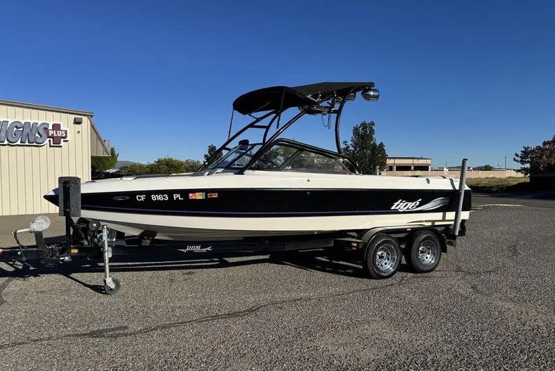 Slide: The Image of 1999 Tigé 2100V Limited boat on trailer, parked outdoors under clear blue sky. - 50
