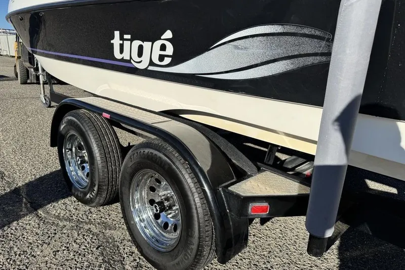 Slide: The Image of 1999 Tigé 2100V Limited boat on trailer, showcasing sleek design and dual wheels. - 59