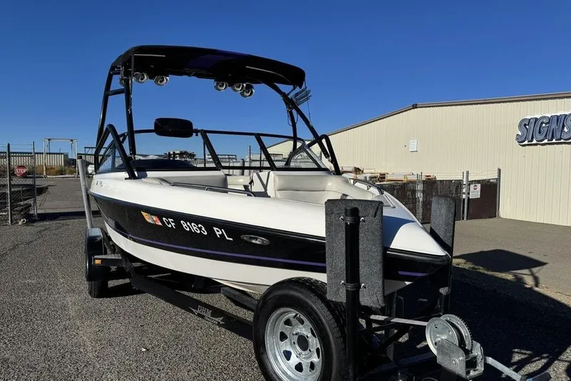Slide: The Image of 1999 Tigé 2100V Limited boat on trailer, parked outdoors under clear blue sky. - 6