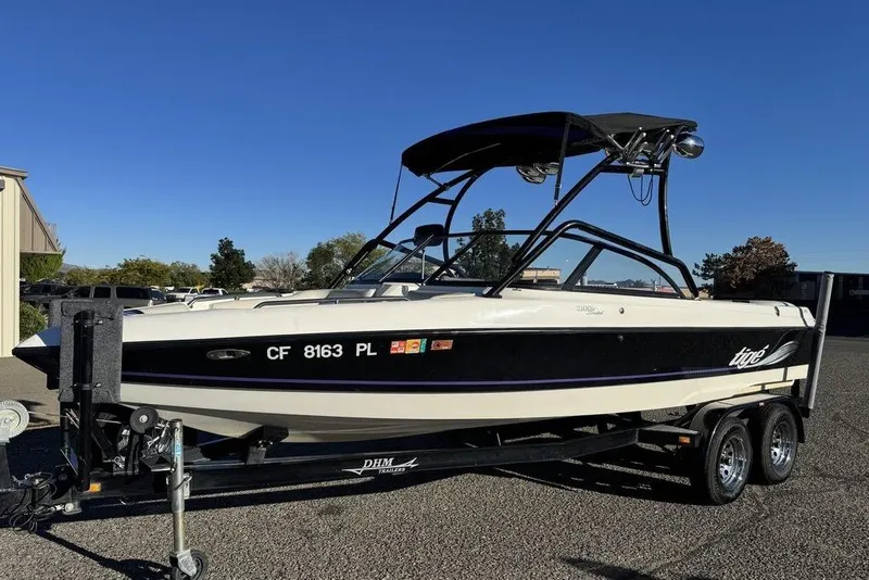 Slide: The Image of 1999 Tigé 2100V Limited boat on trailer, parked outdoors under clear blue sky. - 63
