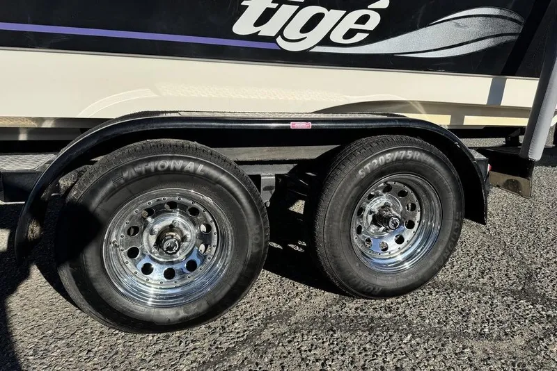 Slide: The Image of 1999 Tigé 2100V Limited trailer with dual chrome wheels on asphalt. - 64
