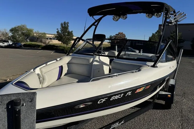 Slide: The Image of 1999 Tigé 2100V Limited boat in parking lot, featuring sleek design and spacious seating. - 66
