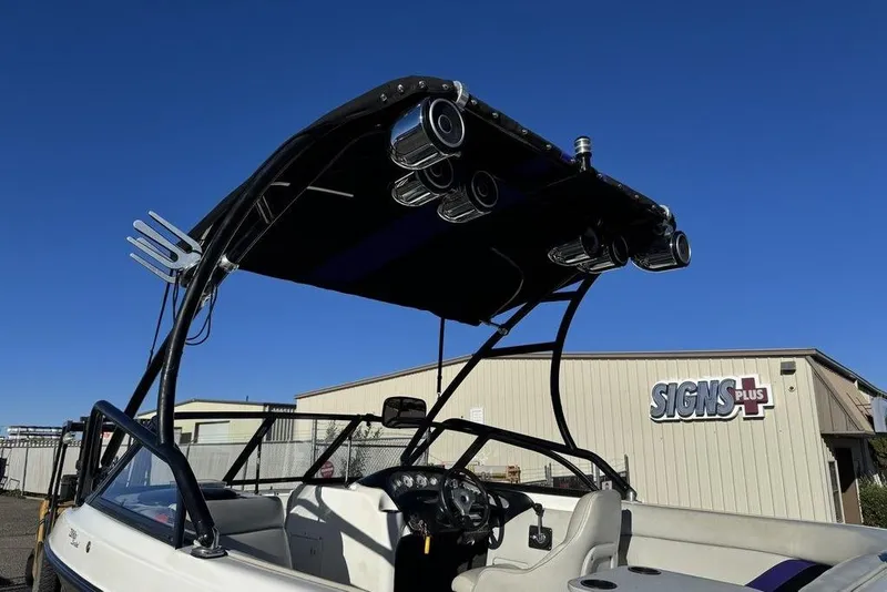 Slide: The Image of 1999 Tigé 2100V Limited boat with wakeboard tower and speakers, parked near Signs Plus building. - 67
