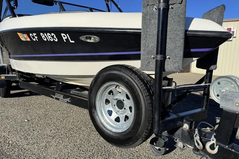 Slide: The Image of 1999 Tigé 2100V Limited boat on trailer, featuring black and white design with visible registration. - 9