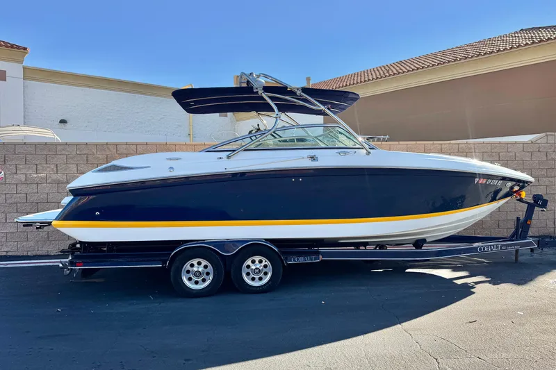 The Image of 2007 Cobalt 252 boat on trailer, parked outdoors, featuring sleek design and navy blue hull. - 0