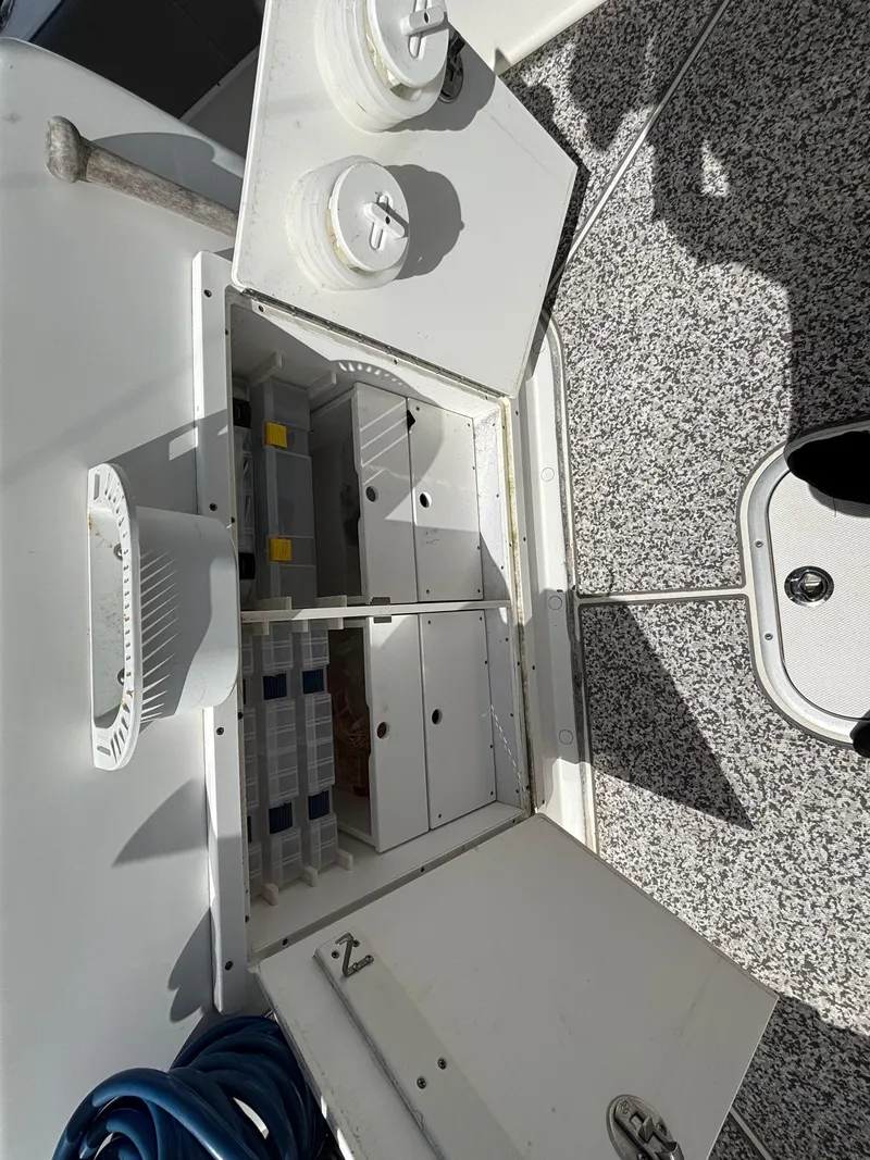 Slide: The Image of 2019 Cape Horn 24 OS storage compartment with organized tackle boxes and fishing gear. - 33