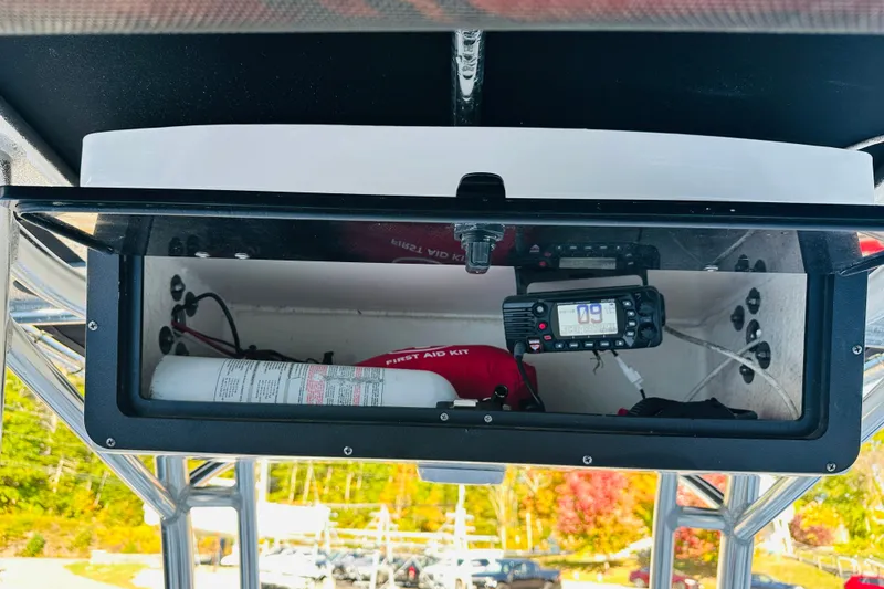 Slide: The Image of 2022 Key West 239 FS boat storage compartment with first aid kit and radio equipment. - 13