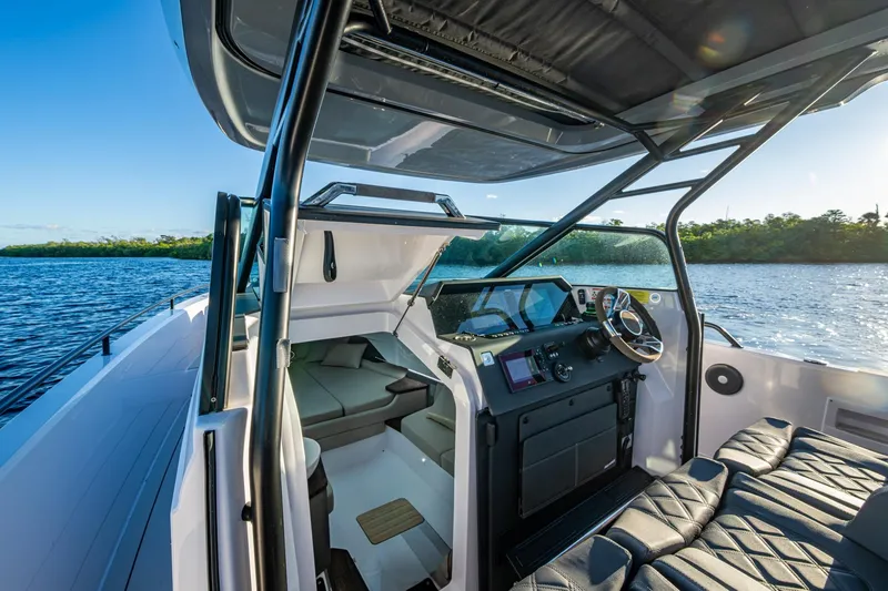 Slide: The Image of 2021 Axopar 37 boat interior with modern cockpit and seating, cruising on a serene lake. - 10