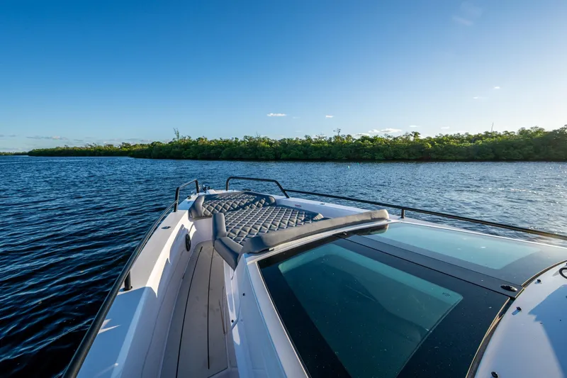 Slide: The Image of 2021 Axopar 37 boat cruising on a sunny day, surrounded by calm waters and lush greenery. - 11