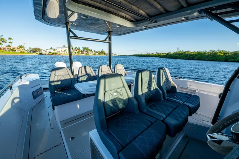 Slide: The Image of 2021 Axopar 37 boat interior with luxurious seating on a scenic waterway. - 17