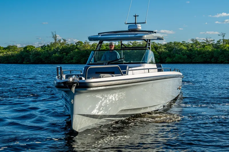 Slide: The Image of 2021 Axopar 37 boat cruising on a sunny day, surrounded by lush greenery. - 34