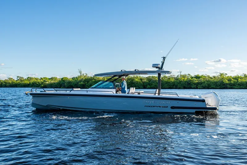 Slide: The Image of 2021 Axopar 37 boat cruising on a sunny day, surrounded by lush greenery. - 37