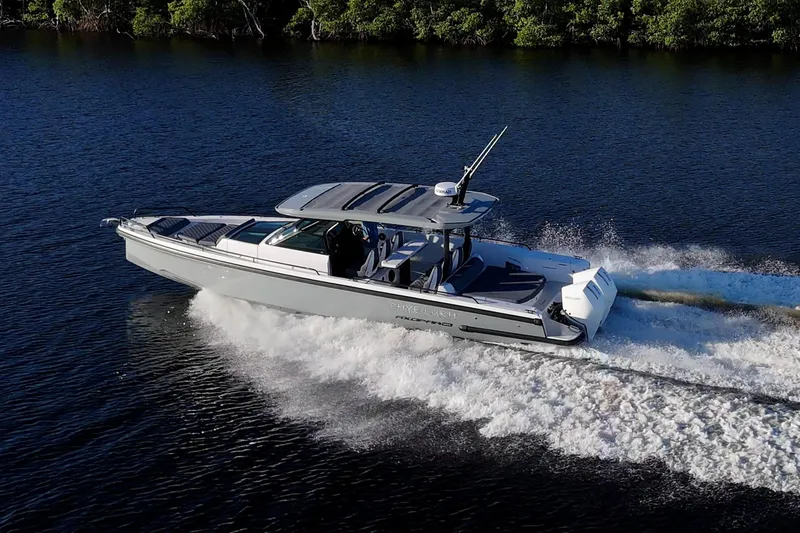 Slide: The Image of 2021 Axopar 37 boat cruising on a serene waterway with lush greenery. - 4