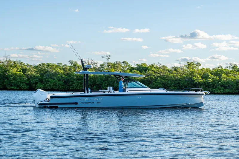 Slide: The Image of 2021 Axopar 37 boat cruising on a calm river with lush green trees. - 44